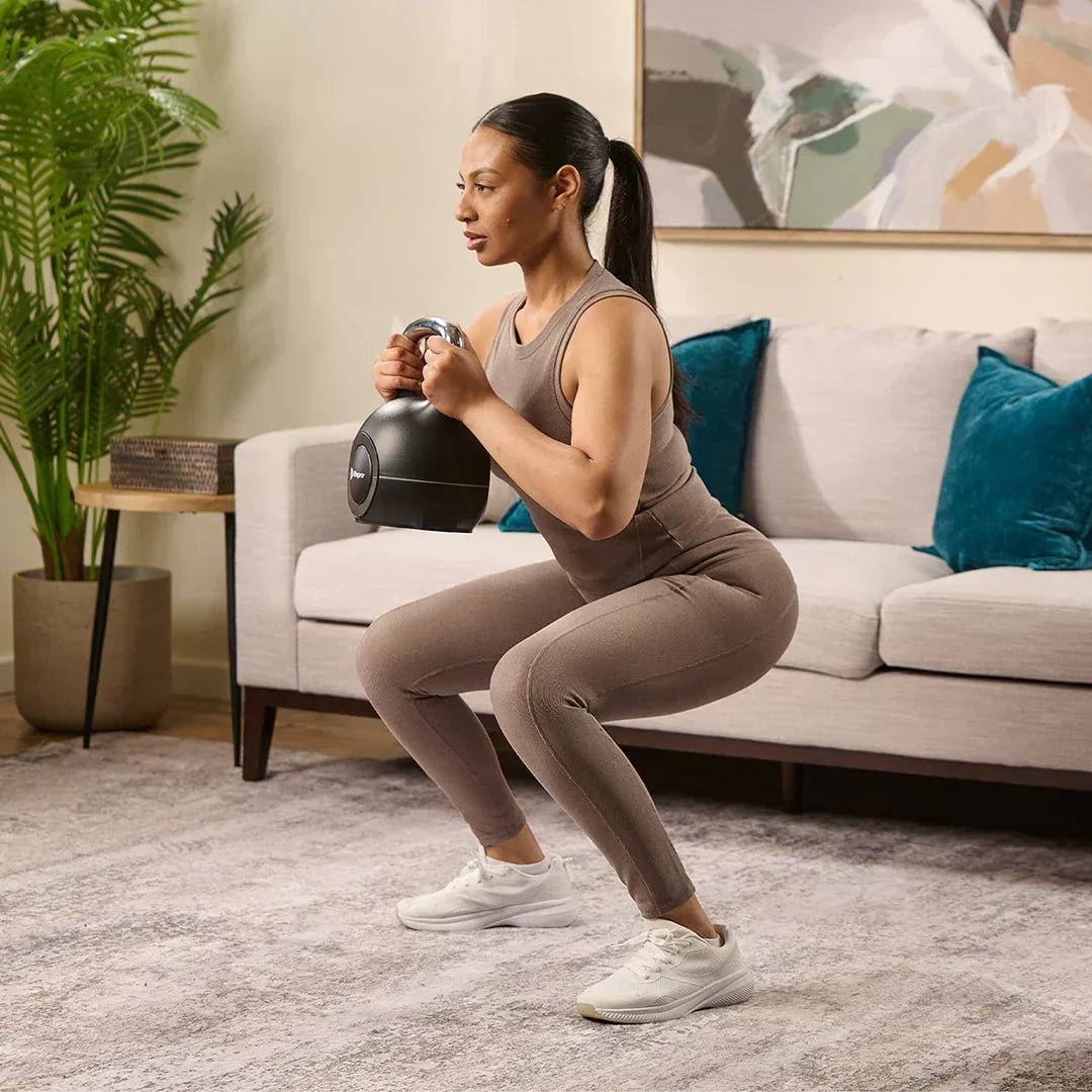 Woman doing a squat while holding a PowerStone kettlebell close to her chest.