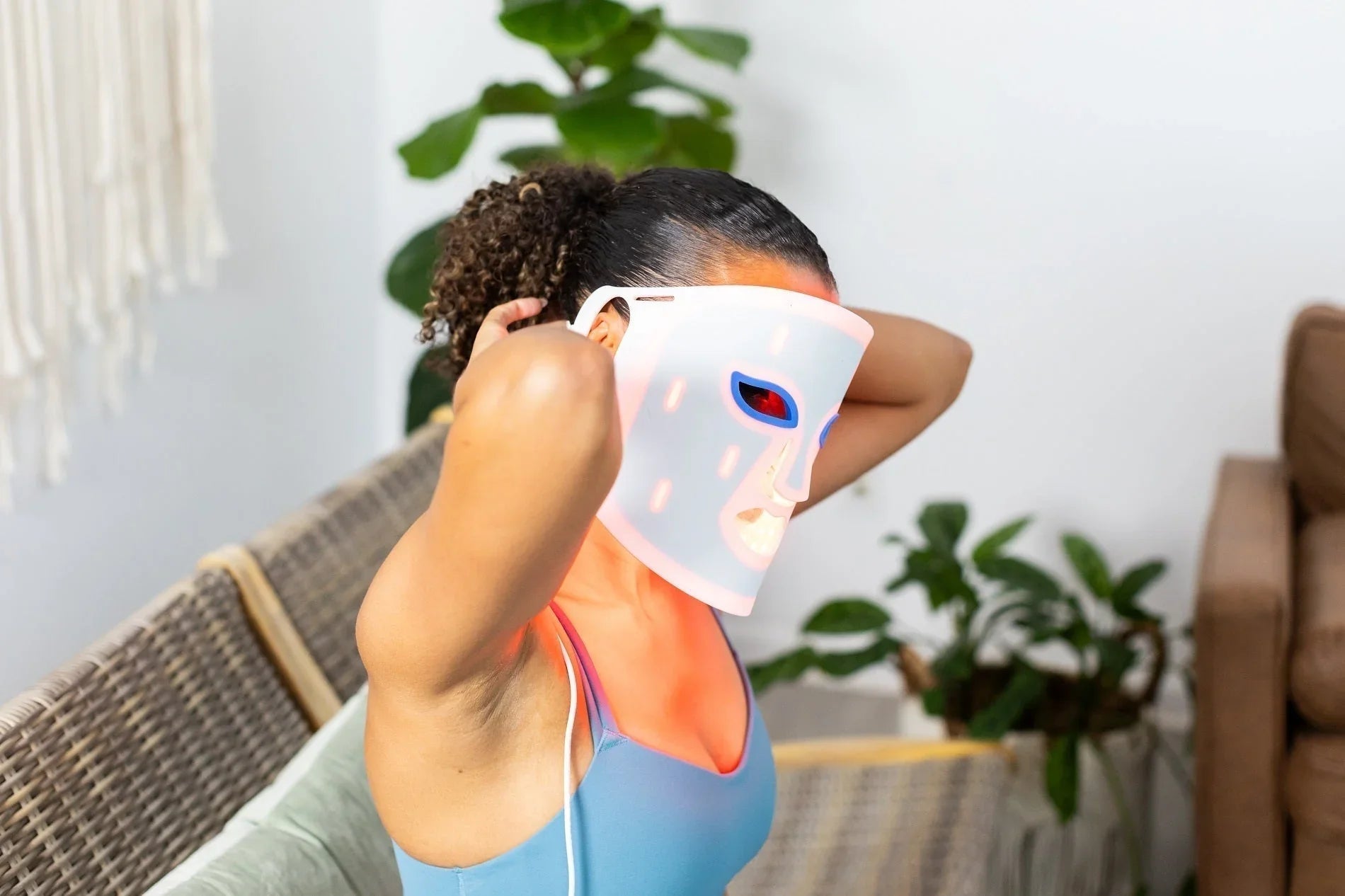 Woman putting on a red light therapy mask