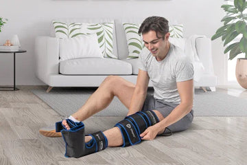 A sitting man uses a CryoFrost Compression System