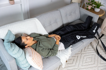 woman laying on couch wearing compression leg massager