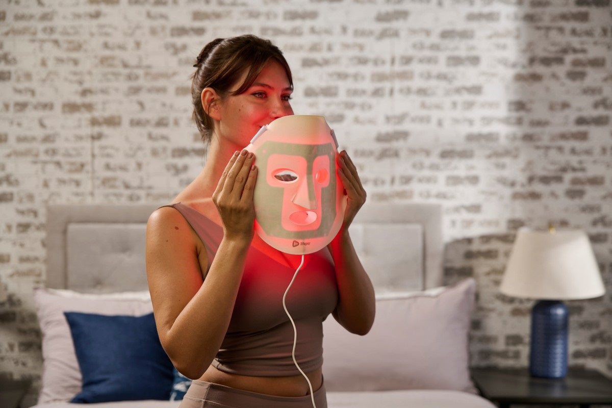 Woman holding red light therapy face mask