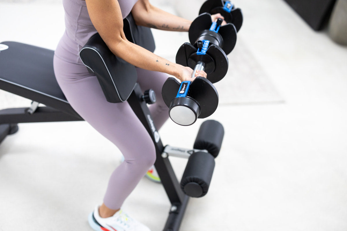 Woman using dumbells on preacher curl bench
