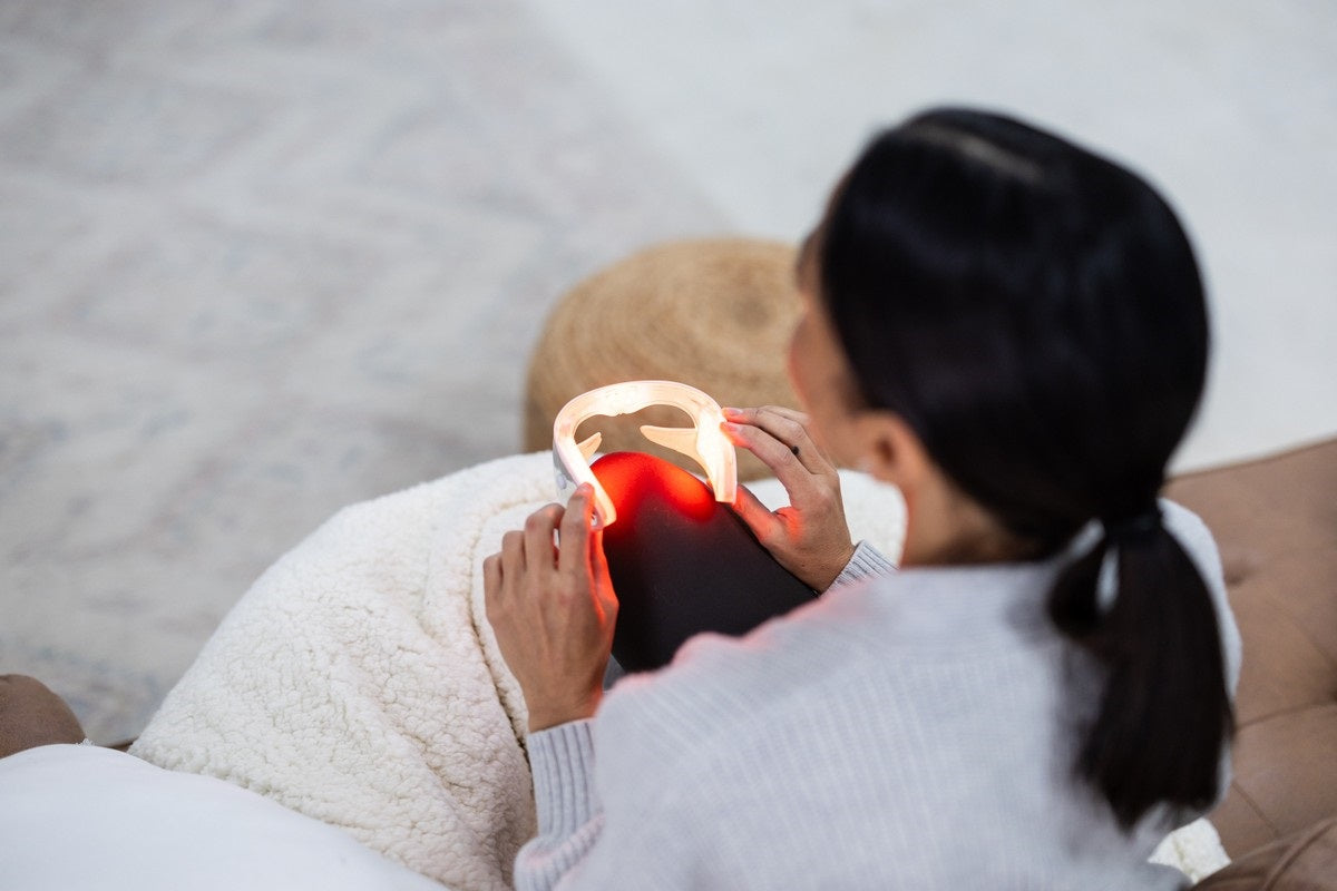 Woman sitting with red light eye therapy mask in her lap