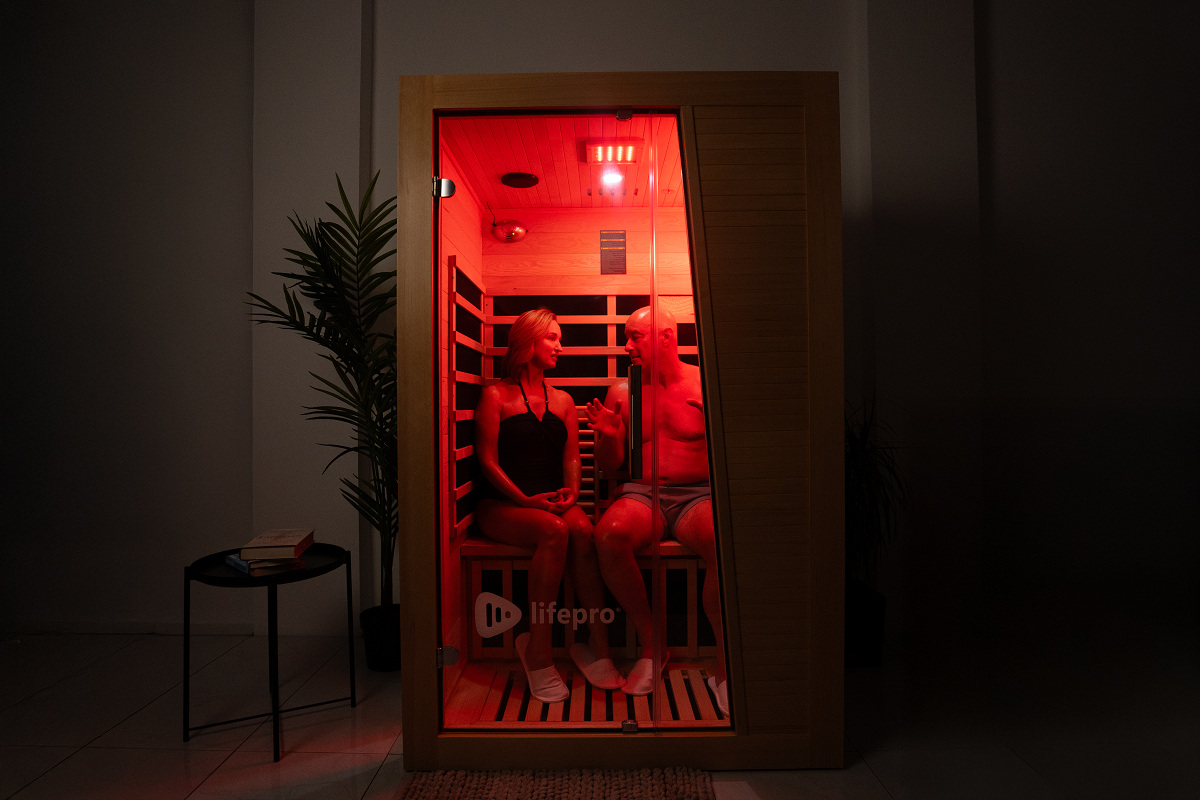 A couple relaxing and talking inside a wooden infrared sauna.