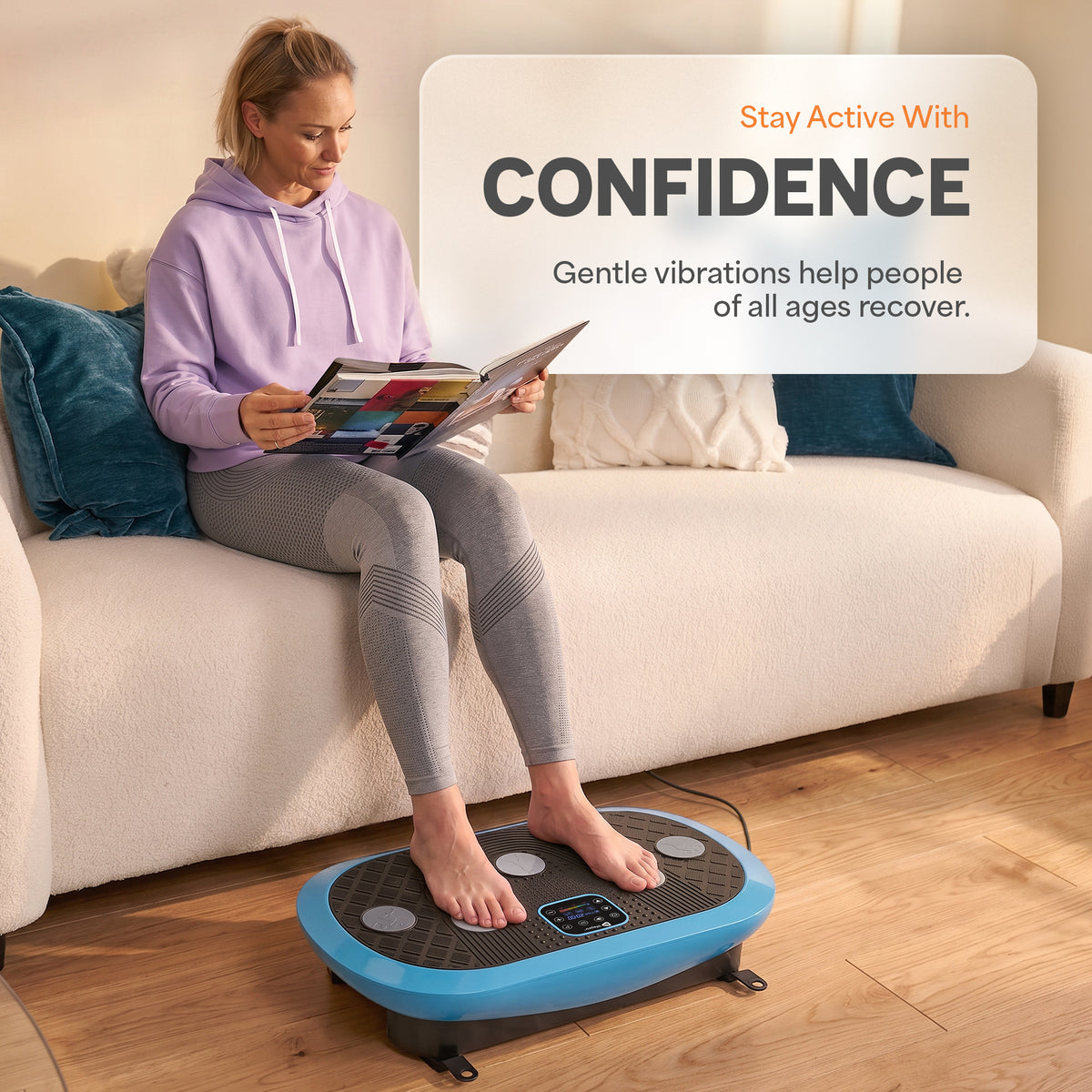 A woman sits on a cream sofa reading a magazine while using a blue and black personal massager on the wooden floor in front of her. The text overlay reads 'Stay Active With CONFIDENCE Gentle vibrations help people of all ages recover.