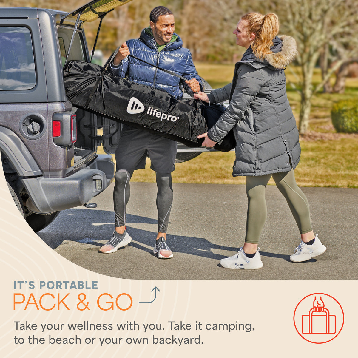 Man and woman carrying the folded ZenZone sauna tent in its LifePro-branded carry bag from a car trunk, captioned 'It's Portable: Pack & Go — Take your wellness with you. Take it camping, to the beach or your own backyard.'
